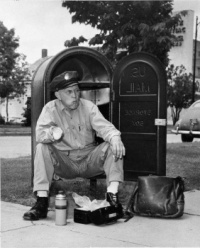 A mailman stops and sits in a mailbox to eat his lunch in Hays, Kansas. (1951)