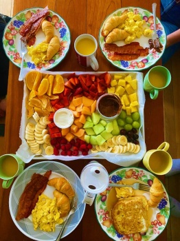 Brunch with scrambled eggs, bacon, croissants, French toast, orange juice, and fruit