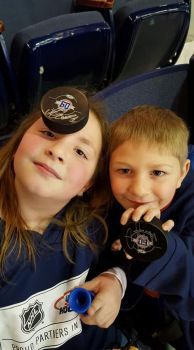 Georgie & Braydon sporting hockey pucks signed by their beloved Amerks team