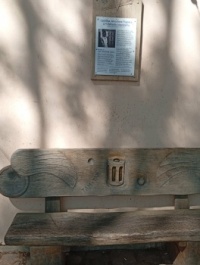 Venku na vodnickém domě pamětní deska a pod deskou lavička se symbolem ,,Ježka v kleci,,...