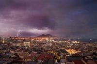 Purple lightning bolts split the sky above Mount Vesuvius.