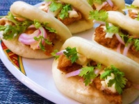 Bao sandwiches with fried chicken pieces, coconut sriracha mayo, and onions