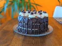 Black Forest cake topped with chocolate ganache, whipped cream, and amarena cherries