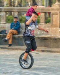 photo of a father giving his son a ride on a unicycle in a park in Mexico City, Mexico