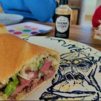 Steak, cheese and spring onion sandwich on a plate with portrait of Max Tooney!