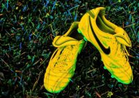 Yellow soccer shoes on colorful grass . .