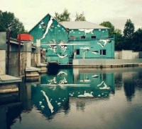 Images painted backwards on building so as to appear normal on the water. pretty cool.