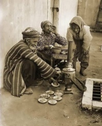 A man sells tea in a street ، Baghdad 1920.  Look how he's rigged the Samovar so he can carry it over his shoulder.