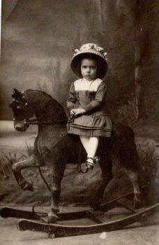Victorian Child sitting (Side-Saddle) On A Rocking Horse