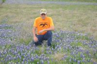 My husband kneeling in the bluebonnets around Austin, TX