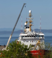 A crane supports a basket that allows technicians to service a Canadian Coast Guard ship.